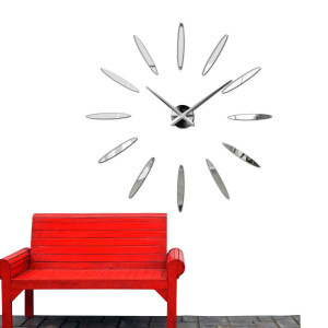 Nástěnné hodiny s velkými zlatými indexy a stříbrnými ručičkami, nalepované přímo na zeď