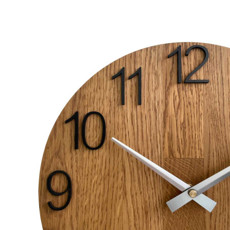 Dřevěné hodiny se symetrickým tvarem a výřezem inspirovaným motivy z přírody.