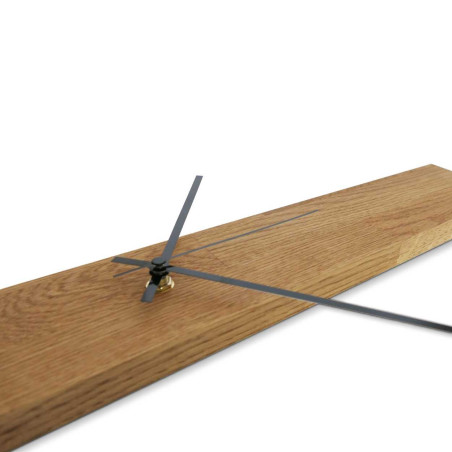 Minimalistické hodiny ze dřeva ve tvaru úzkého panelu se stříbrnými a černými ručičkami. Minimalistické hodiny ze dřeva ve tvaru úzkého panelu se stříbrnými a černými ručičkami.